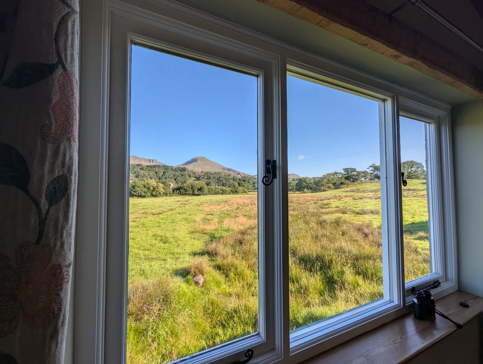 View of Coniston Old Man across the field through the dining room window at Ellis Howe in Torver on a clear sunny morning
